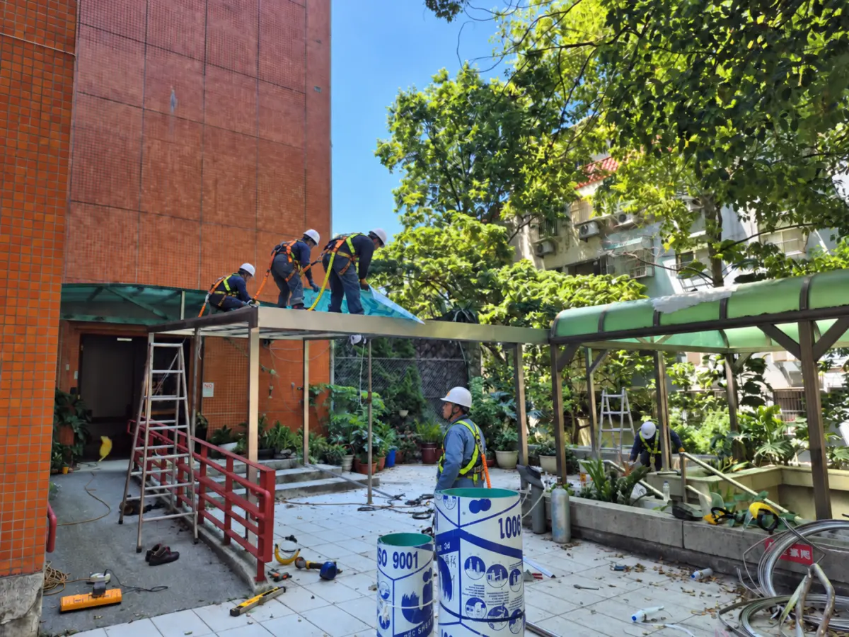 施工中不鏽鋼方管骨架搭建與PC板安裝，工人進行焊接與固定作業